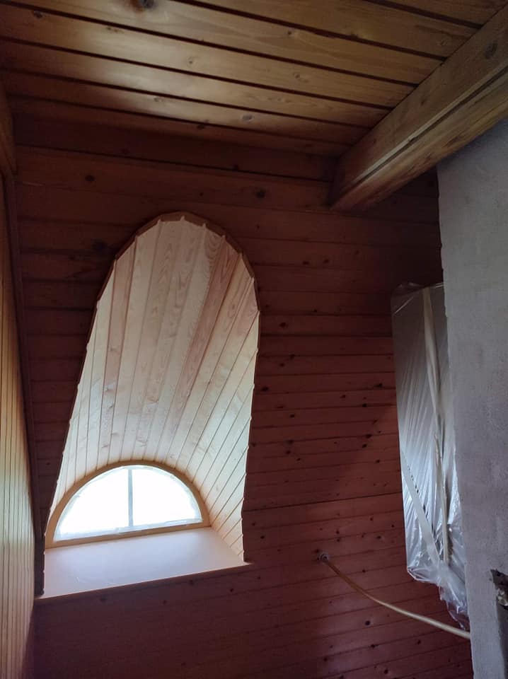 Trævæg og loft med buet vindue i loftsrum