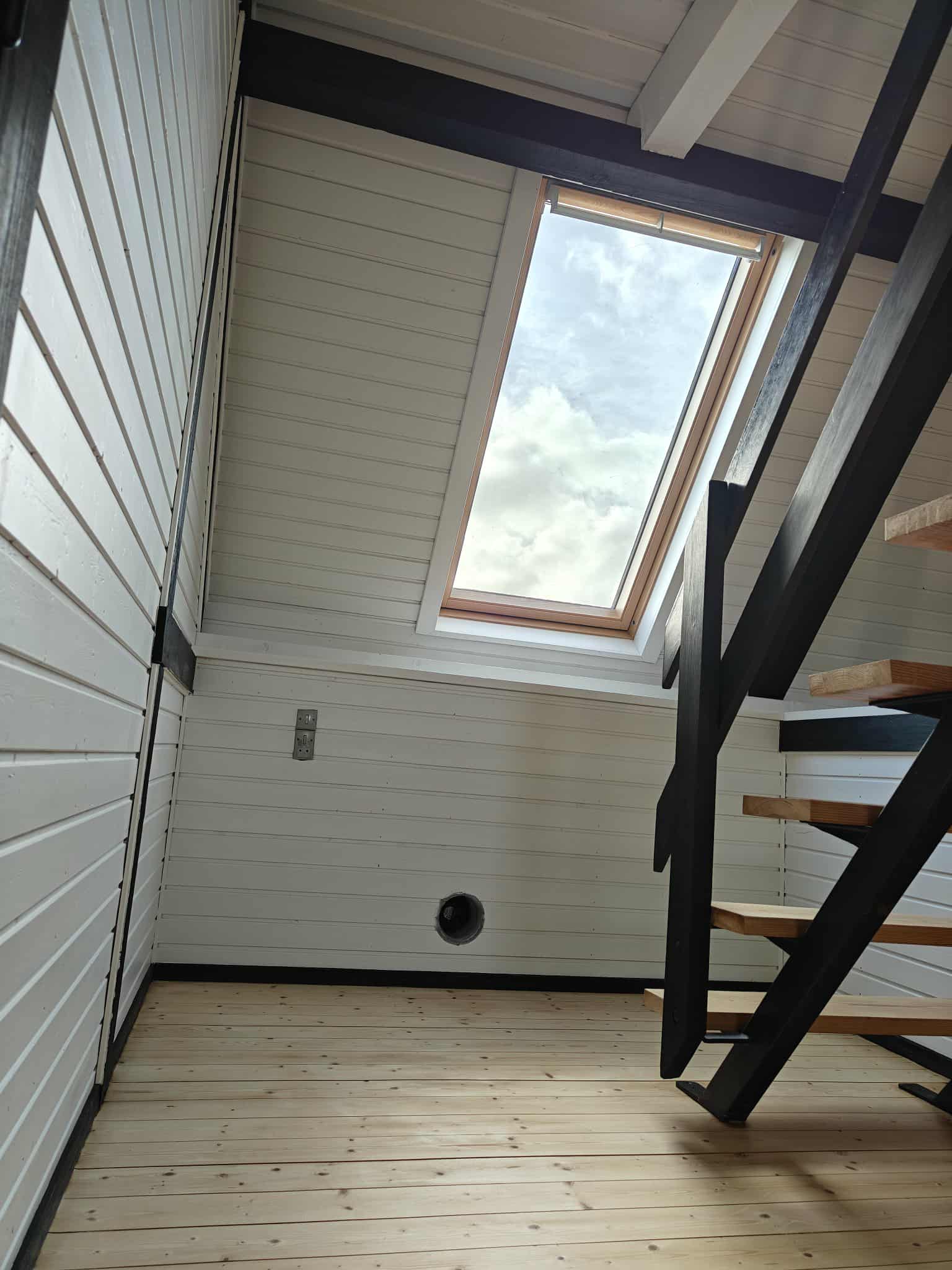 Lyst loftsrum med ovenlysvindue og trappe